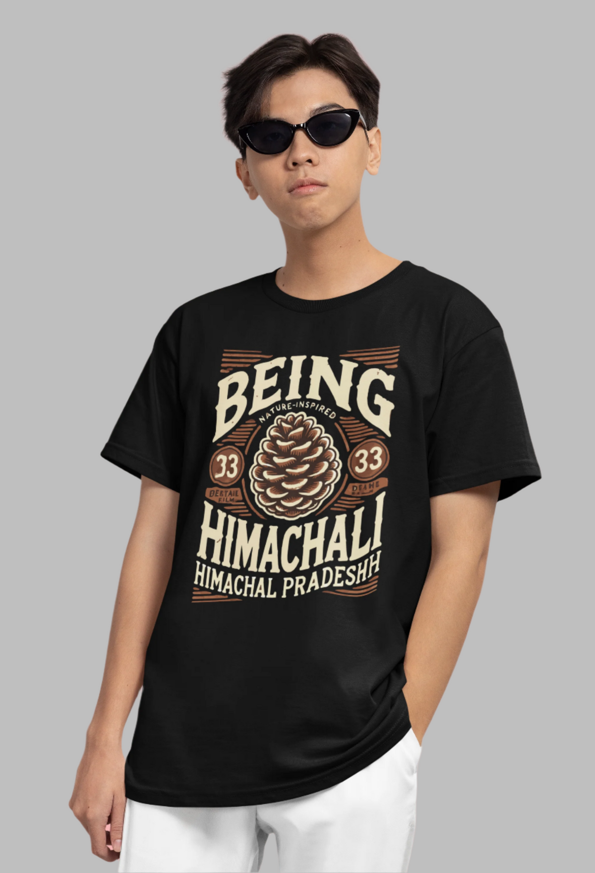 "black t-shirt featuring an intricate pine cone illustration paired with bold 'Being Himachali' typography. The design celebrates the natural beauty and heritage of Himachal Pradesh, with a detailed pine cone symbolizing the region's mountain spirit."